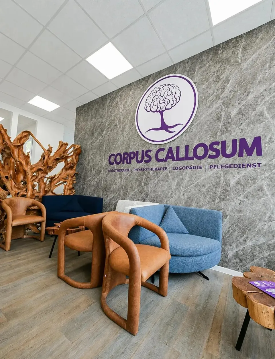 Empfang von Corpus Callosum in Dortmund: Logowand mit lila Schriftzug, Ledersessel und Holzskulptur