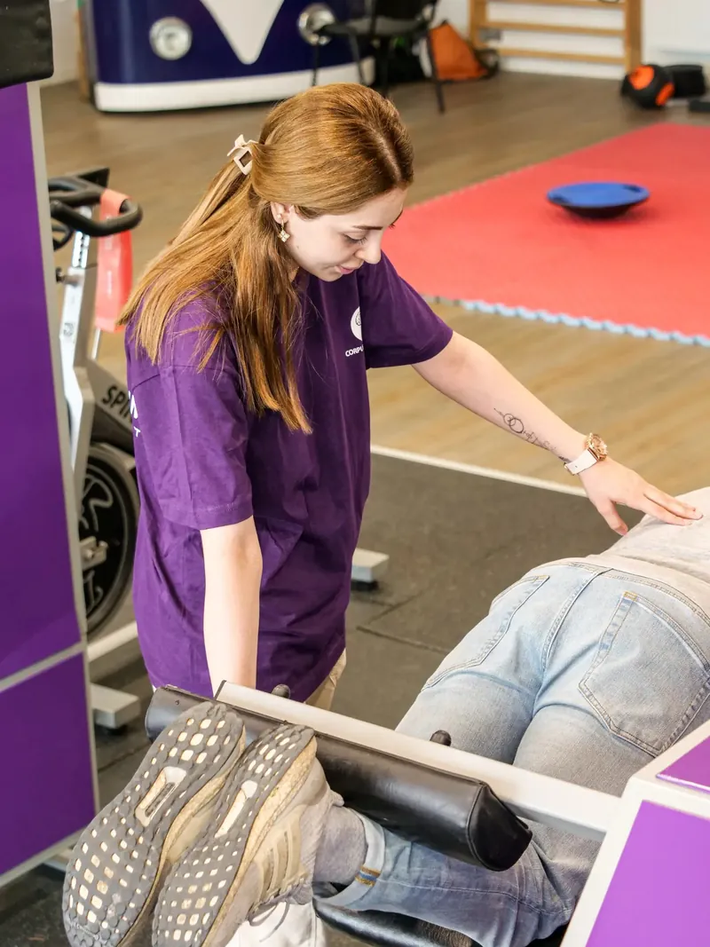 Physiotherapeutin betreut eine Person an einem Rückentrainingsgerät