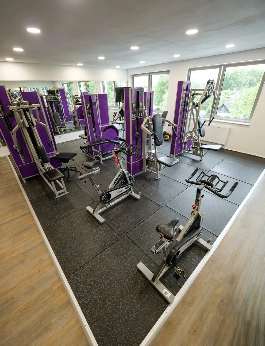 Helle Trainingsfläche mit lila Trainingsgeräten und großen Fenstern